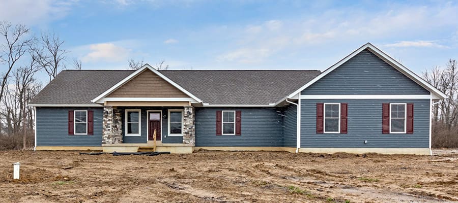 Custom ranch home with stone columns, blue siding and cranberry colored shutters.